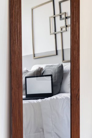 Foto de Reflejo de cama y portátil en el espejo. Diseño clásico moderno. Cómodo interior del hogar. - Imagen libre de derechos