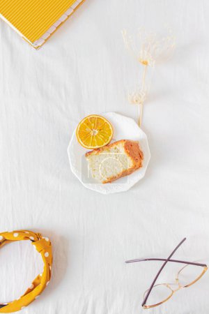 Photo for Home office composition with orange piece of cake, glasses, headband and planner on white background. Flat lay, top view still life concept. - Royalty Free Image