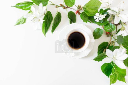 Téléchargez les photos : Tasse blanche avec café noir frais décoré de feuilles vertes, fleurs blanches - en image libre de droit