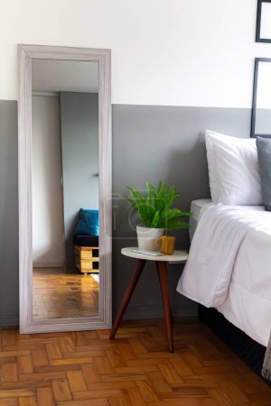 Foto de Cómodo interior de la casa. Reflejo de cama en el espejo con plantas de interior verdes. - Imagen libre de derechos