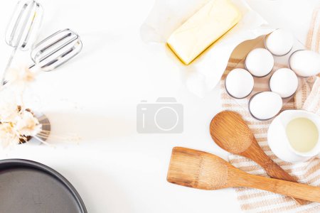 Foto de Menaje de cocina, concepto de preparación de pasteles sobre fondo blanco. vista superior de utensilios de madera, mantequilla, huevos y paño de cocina. - Imagen libre de derechos