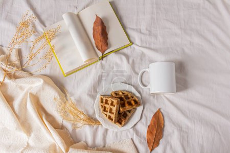 Photo for Breakfast in bed with coffee mug and waffles on messy bed - Royalty Free Image