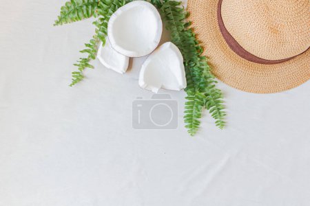 Téléchargez les photos : Chapeau de paille, noix de coco et feuilles vertes. Accessoire féminin pour l'été. Concept de mode. - en image libre de droit