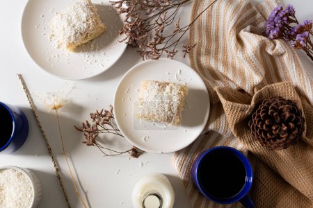 Photo for Top view of breakfast cozy composition with coconut cake in plates and mugs of coffee - Royalty Free Image
