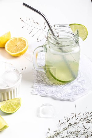 Téléchargez les photos : Concept de boissons fraîches d'été. Verre avec limonade verte et agrumes tranchés sur fond blanc. - en image libre de droit