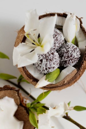 Photo for Chocolate and coconut candies on coconut bowl decorated with white flower - Royalty Free Image