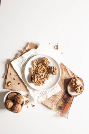 Photo for Cosy autumn composition of walnuts in white plate and craft paper on white background. - Royalty Free Image