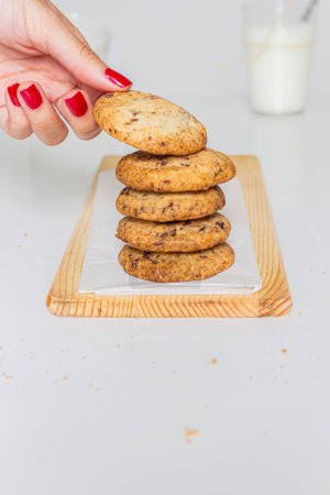 Téléchargez les photos : Biscuits faits maison sur planche à découper en bois et un verre de lait sur fond blanc. - en image libre de droit