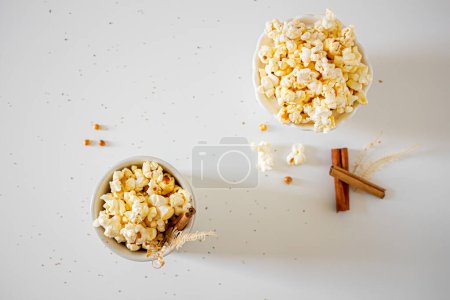 Photo for Top view of popcorn in bowls with cinnamon sticks on white background. Autumn, winter food concept. - Royalty Free Image