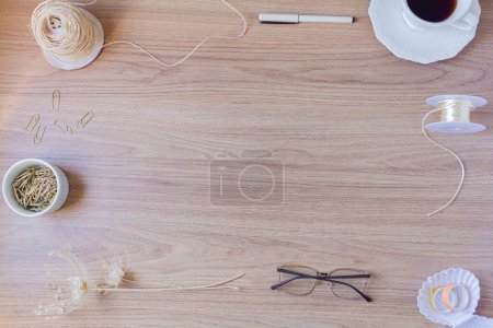 Foto de Marco hecho de taza de café, pluma, clips de papel, vasos, cuerdas y flores secas sobre fondo de madera. - Imagen libre de derechos