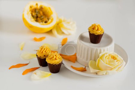 Foto de Cupcakes caseros en utensilios de cocina con fruta de la pasión y pétalos florales alrededor - Imagen libre de derechos