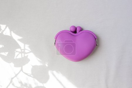 Téléchargez les photos : Portefeuille en forme de coeur violet sur fond blanc, avec quelques feuilles ombre. - en image libre de droit