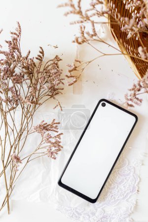 Photo for Dried Lilac Flowers Bouquet and mobile phone on white background. - Royalty Free Image