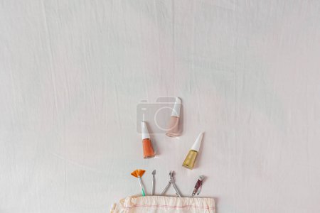 Foto de Blog de belleza, composición de manicura con esmalte de uñas y herramientas de manicura procedentes de una bolsa de algodón - Imagen libre de derechos