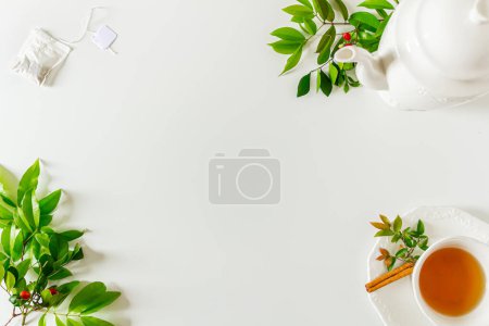 Foto de Taza de marco de té con tetera, bolsa de té y hojas verdes sobre fondo blanco. Piso tendido, vista superior. - Imagen libre de derechos