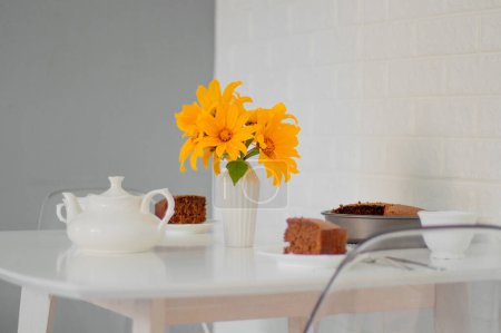 Téléchargez les photos : Bouquet de tournesols jaunes en vase sur la table avec des morceaux de gâteau et théière - en image libre de droit