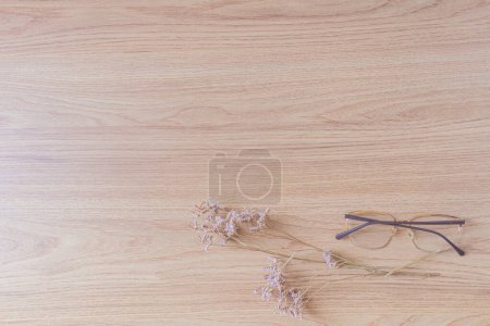 Foto de Gafas graduadas con flores lila sobre mesa de madera - Imagen libre de derechos