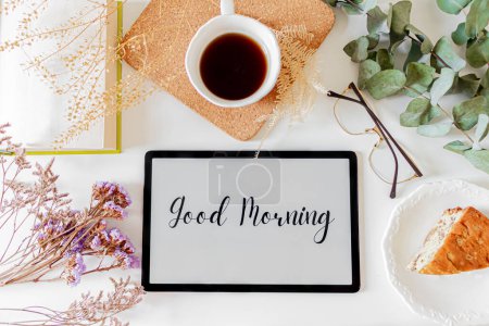 Photo for Phrase "good morning" on a tablet, floral frame and breakfast composition on white background. Slow morning concept. - Royalty Free Image
