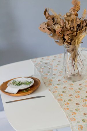 Foto de Vajilla sobre tela de lino con ramo de flores secas en jarrón - Imagen libre de derechos