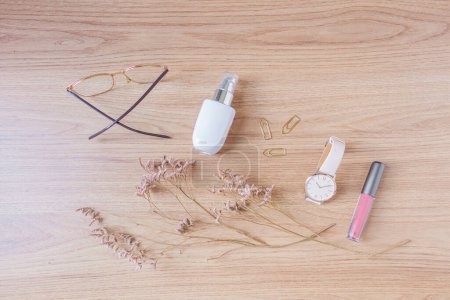 Foto de Accesorios de estilo femenino: gafas, cimientos, clips de papel, reloj de pulsera, lápiz labial sobre fondo de madera. - Imagen libre de derechos