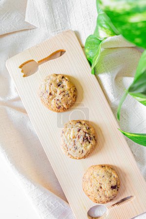 Photo for Homemade cookies on a cutting board on linen fabric and boa leaves on white background - Royalty Free Image
