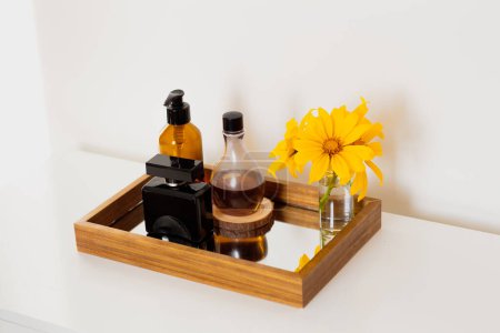 Téléchargez les photos : Ensemble de flacons de parfum avec des fleurs jaunes sur plateau miroir. Composition esthétique minimaliste beauté. - en image libre de droit
