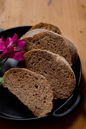 Téléchargez les photos : Tranches de pain brun sur une table en bois. Composition sombre. Concept de boulangerie. - en image libre de droit