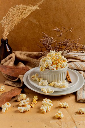 Photo for Cozy and aesthetic beige composition with popcorn decorated with dried plants. Autumn, winter food concept. - Royalty Free Image