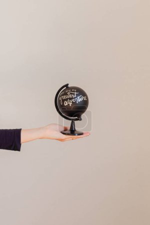 Téléchargez les photos : Main féminine tenant un globe noir écrit : "vous êtes ma plus grande aventure" - en image libre de droit