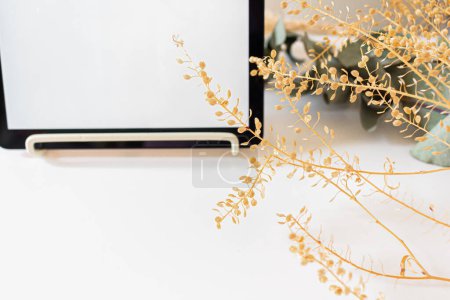 Photo for Top view of digital tablet decorated with dried flowers on white background - Royalty Free Image