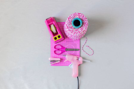 Photo for Craft essentials. Pink string, scissors, stapler, duct tape holder and hot glue gun on a white background. Do it yourself concept. - Royalty Free Image