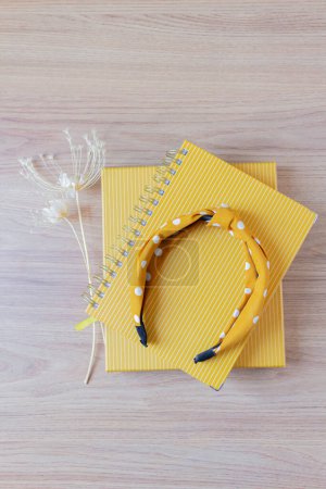 Photo for Female home office desk workspace with yellow planners, wild flowers and headband on a wooden table. - Royalty Free Image