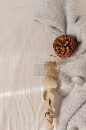 Téléchargez les photos : Composition hivernale. Une tasse de café couchée sur le lit en lin beige avec des chaussettes chaudes brunes, de l'eucalyptus et du pin. Lifestyle, mode concept saisonnier. - en image libre de droit