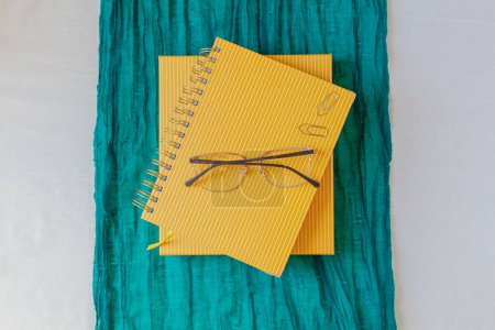 Téléchargez les photos : Pose plate fixe avec des planificateurs de moutarde, trombones dorés, écharpe verte et lunettes. - en image libre de droit