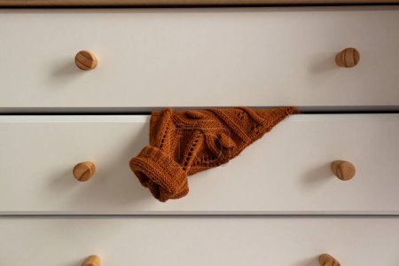 Photo for Stylish beige dresser, brown sweater on a drawer. Vintage interior design. Comfortable home. Autumn concept. - Royalty Free Image