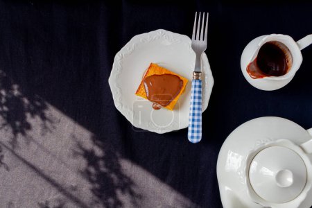 Photo for Breakfast concept. Tasty peace of Brazilian Carrot Cake with chocolate and teapot aside - Royalty Free Image