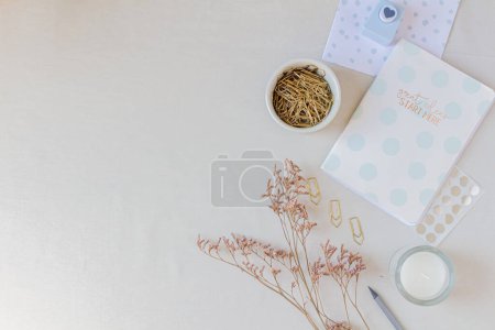 Photo for Polka dot notebook, golden paper clips, candle, heart shaped paper cutter, dried flower branches and pencil. Stationary concept. Flat lay, top view on white background. - Royalty Free Image