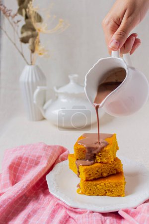 Téléchargez les photos : Table de service avec tranches de gâteau aux carottes brésiliennes, main féminine versant le chocolat de la cruche sur le gâteau - en image libre de droit
