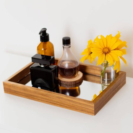 Foto de Set de frascos de perfume con flores amarillas en bandeja espejo. Composición estética minimalista de belleza. - Imagen libre de derechos