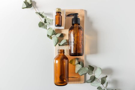 Photo for Brown glass bottles, soap and eucalyptus leaves on white background. - Royalty Free Image
