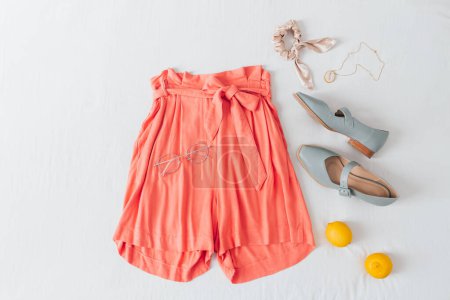 Photo for Summer female fashion stylish composition. Shorts, lemons, glasses, necklace, scrunchie and shoes on white messy bed sheet background. Flat lay, top view. - Royalty Free Image