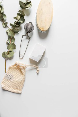 Téléchargez les photos : Fournitures ménagères de style éco beige : planche à découper en bois de savon de coco et feuilles d'eucalyptus sur fond blanc. Couché à plat, vue de dessus. Concept minimaliste respectueux de l'environnement. - en image libre de droit