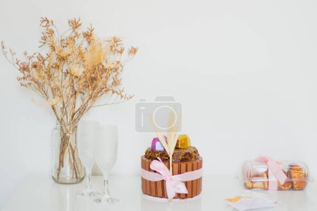 Photo for Romantic concept. Chocolate cake with two empty glasses, bouquet of dried flowers on white table - Royalty Free Image