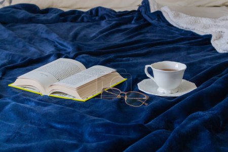 Téléchargez les photos : Lit désordonné, livre, verres et une tasse de thé sur un matin paresseux automne - en image libre de droit