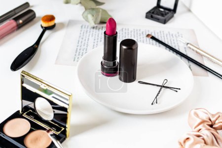 Téléchargez les photos : Cosmétiques, pinceau de maquillage et rouge à lèvres sur une table blanche - en image libre de droit