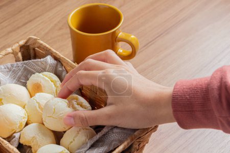Téléchargez les photos : Jeune femme boire du café et manger du pain au fromage pendant le petit déjeuner - en image libre de droit