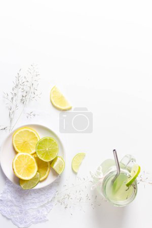 Téléchargez les photos : Concept de boissons fraîches d'été. Vue du dessus du verre avec de la limonade verte et des agrumes tranchés sur fond blanc. - en image libre de droit