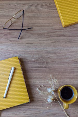 Téléchargez les photos : Espace de travail de bureau féminin avec une tasse de café, un planificateur, des lunettes, un stylo et des fleurs sauvages sur une table en bois. Couché plat, vue du dessus. - en image libre de droit
