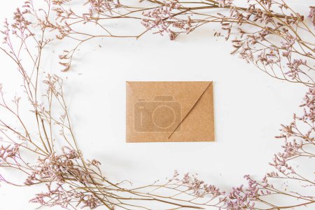 Téléchargez les photos : Cadre rond avec fleurs lilas et enveloppe en papier artisanal. Couché plat, vue du dessus. - en image libre de droit