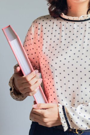 Foto de Recortado disparo de mujer joven sosteniendo libro rosa - Imagen libre de derechos